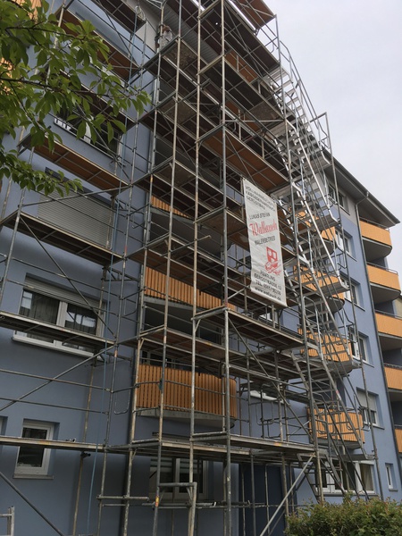 Eingerüstete blaue Fassade eines Eckhauses mit Wallauch Firmenfahrzeug